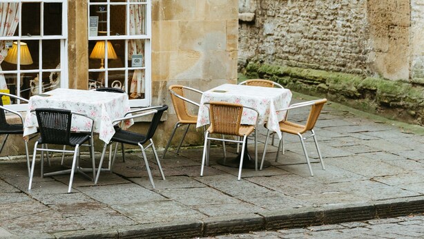 Una acogedora tienda de té llamada "The Bath Bun Tea Shoppe", con terraza y fachada de piedra.