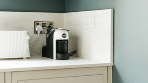 Una kitchenette con cafetera, un enchufe y un armario.