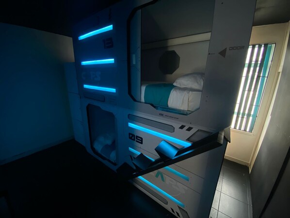 Een futuristische kamer met een stapelbed, een bedieningspaneel en een raam met zonwering.
