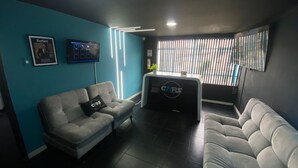 Un salon moderne avec deux canapés gris, une table basse noire et un mur d’accent bleu.