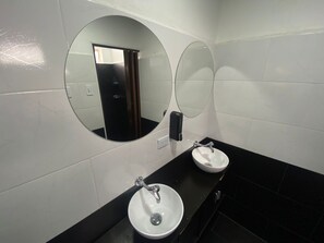 Een badkamer met twee wastafels, een spiegel en een handdroger.