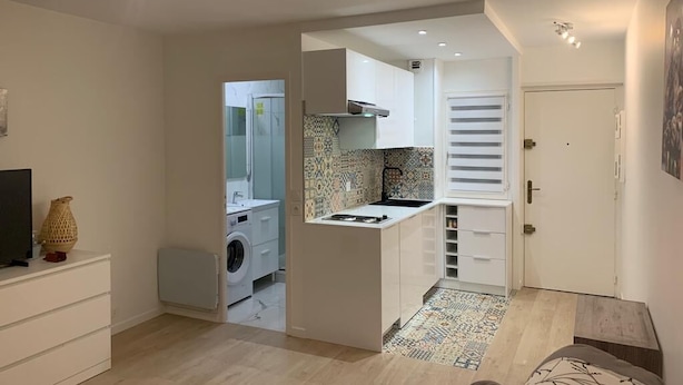 Een compacte keuken met een wasmachine, een klein eiland en een betegelde spatwand.