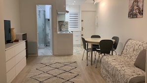Een moderne woonkamer met een bank, een eettafel met stoelen, een keuken en een gang naar een badkamer.