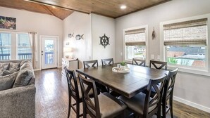 Un coin repas avec une table et des chaises en bois, une décoration en forme de roue de navire et une vue par les fenêtres.