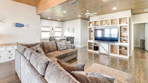 Un salon avec un canapé d’angle, un téléviseur et un plafond en bois.