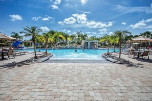 A pool area with lounge chairs, palm trees, and a water slide. - PP8962 - 4 Bedrooms w/ Pool & Resort Access (Kissimmee)