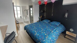 Une chambre à coucher avec un lit, une table de chevet, un miroir et une fenêtre.