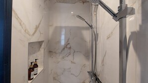 Une douche moderne dotée d’un pommeau de douche à main et d’une pomme de douche fixée au mur.