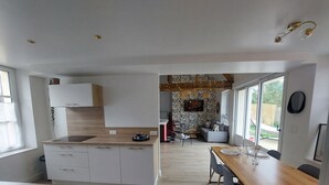 Une cuisine moderne avec des meubles blancs, un plan de travail en bois et un coin repas comprenant une table et des chaises en bois.
