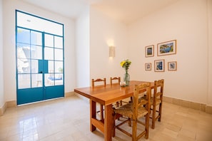Un coin repas avec une table et des chaises en bois, un vase de fleurs et des tableaux encadrés au mur.