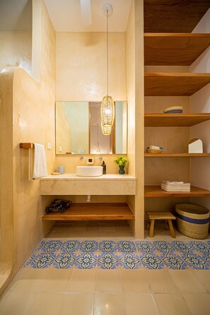 Une salle de bain avec un grand miroir, un lavabo, des étagères et un sol à motifs.