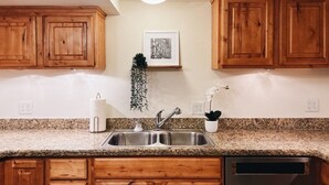 Una cocina con armarios de madera, encimera de granito, pileta de acero inoxidable y lavavajillas.