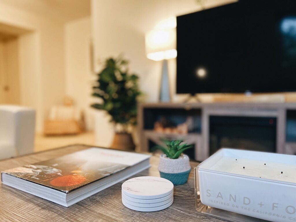 A wooden table with a book, a small potted plant, and a white box with the text "SAND+FO".