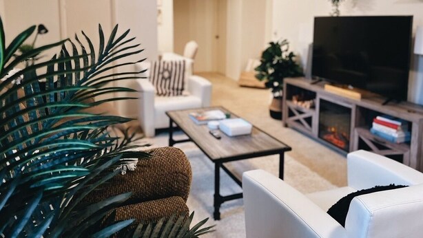 Una sala de estar con un sofá, una mesa de centro, un televisor y una estantería.
