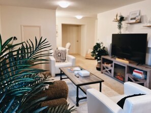 Ein Wohnzimmer mit einer Couch, einem Couchtisch, einem Fernseher und einem Bücherregal.