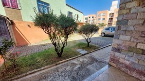 A residential area with a paved pathway, small trees, and a parked car. - Condomínio Santa Mônica (Belo Horizonte)