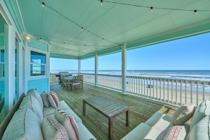 A covered deck with a view of the beach, wooden furniture, and a table. - Beachfront Beauty with Bay Views and Boat Ramp Access (Freeport)