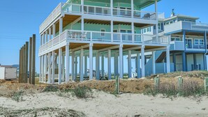 Ett hus i flera våningar som ligger vid stranden, med en balkong på varje våning, en inglasad veranda och en liten tornliknande konstruktion på taket.