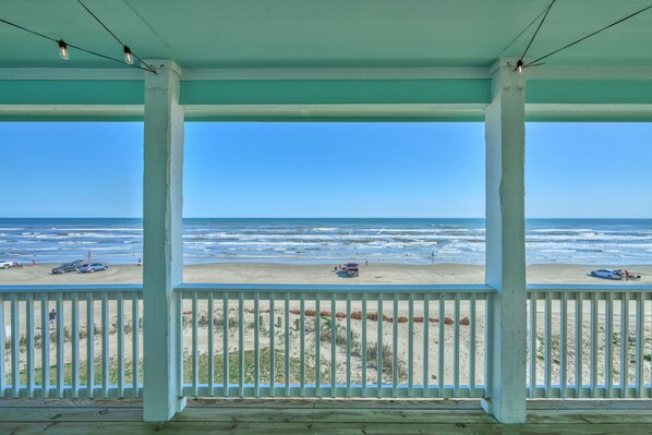 A beach view from a covered porch with a railing, wooden floor, and a clear sky. - Beachfront Beauty with Bay Views and Boat Ramp Access (Freeport)