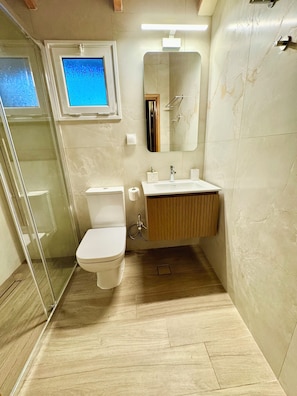 A bathroom with a toilet, sink, and shower.