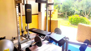 A home gym with a bench press, weight bench, and various exercise equipment. - AHP (Corfu)