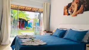 A bedroom with a large bed, a view of a garden, and a painting of lions on the wall. - Pousada Cielo Blu (Búzios)