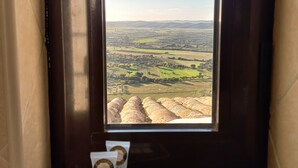 Vista desde una ventana a un paisaje rural con campos y colinas distantes.