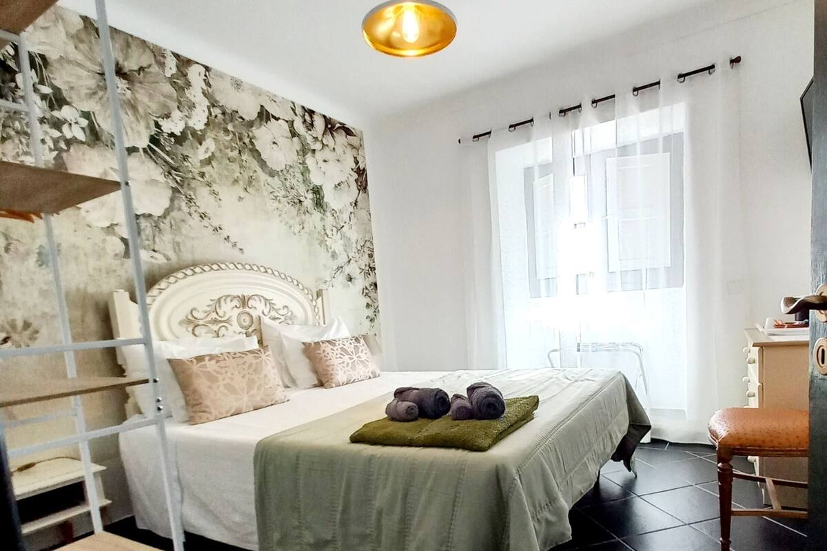 Un dormitorio con una litera, una cama individual, una manta verde y una lámpara colgante.