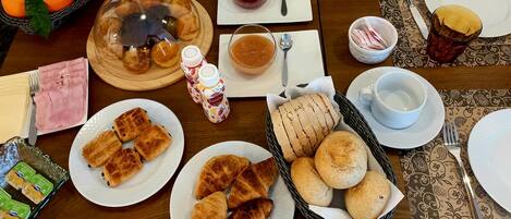 A breakfast setting with bread, pastries, and a fruit basket.