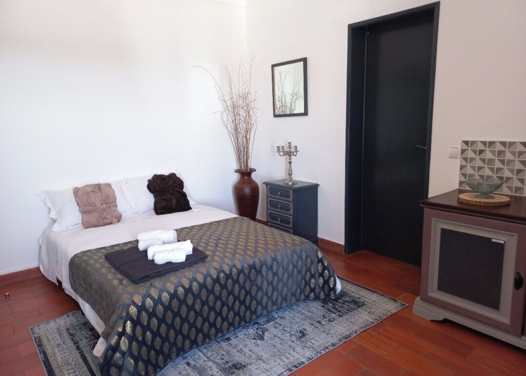 A bedroom with a bed, bedside table, lamp, and a door.