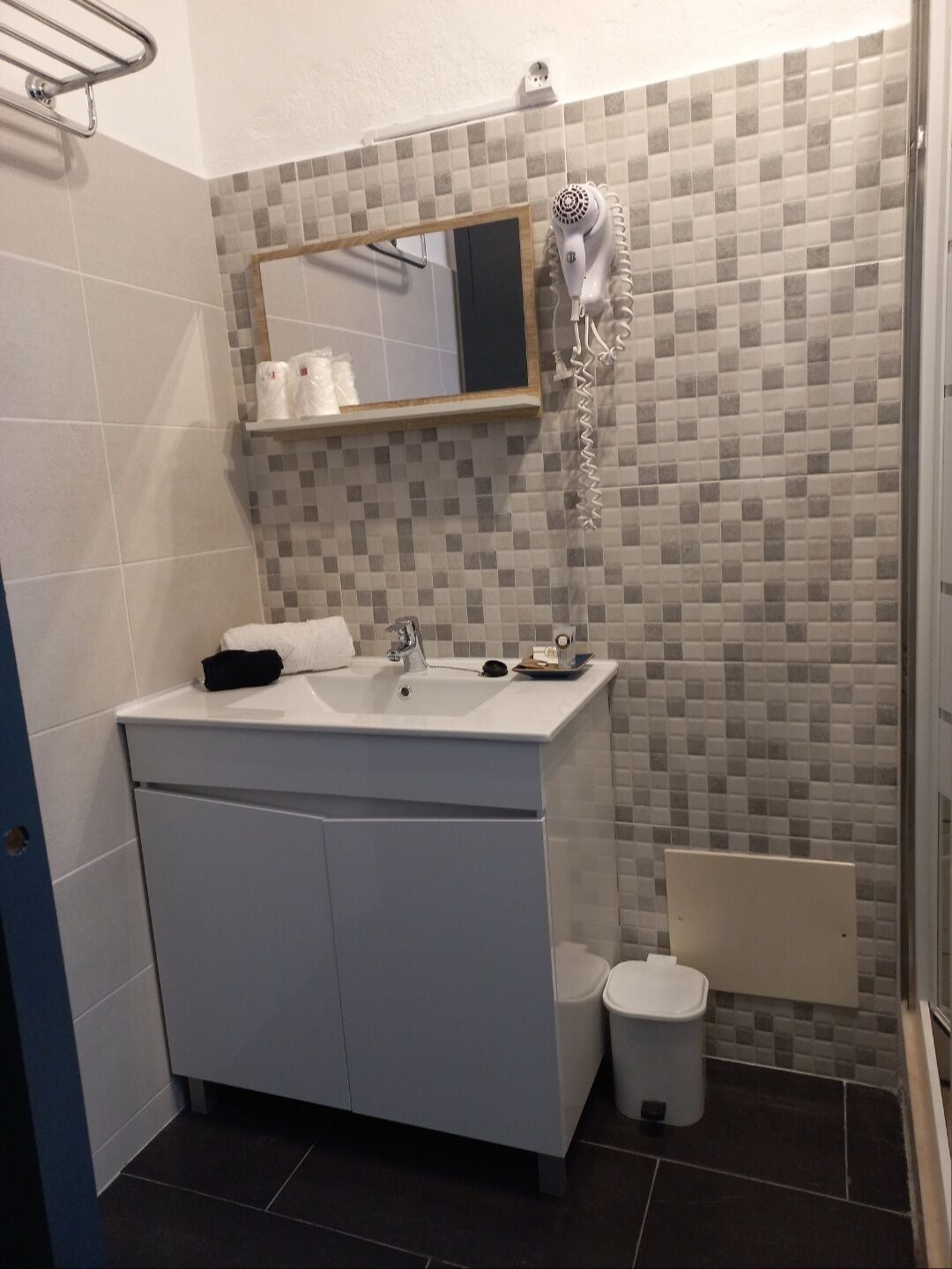 A modern bathroom with a white sink, mirror, and tiled backsplash.