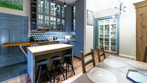 A modern kitchen with a central island, bar stools, and a dining area with a table and chairs. - Opera Apartments (Kraków)