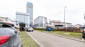 A parking area with cars, a bus, and buildings in the background. - Opera Apartments (Kraków)