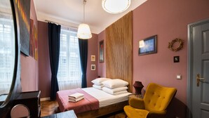 A bedroom with a bed, a chair, a dresser, and a mirror. - Opera Apartments (Kraków)