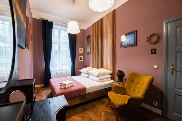 A bedroom with a bed, a chair, a dresser, and a mirror.