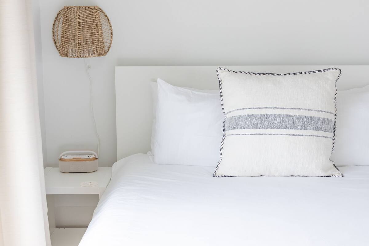 Une chambre à coucher avec un lit, une table de chevet, une lampe et un tableau encadré au mur.
