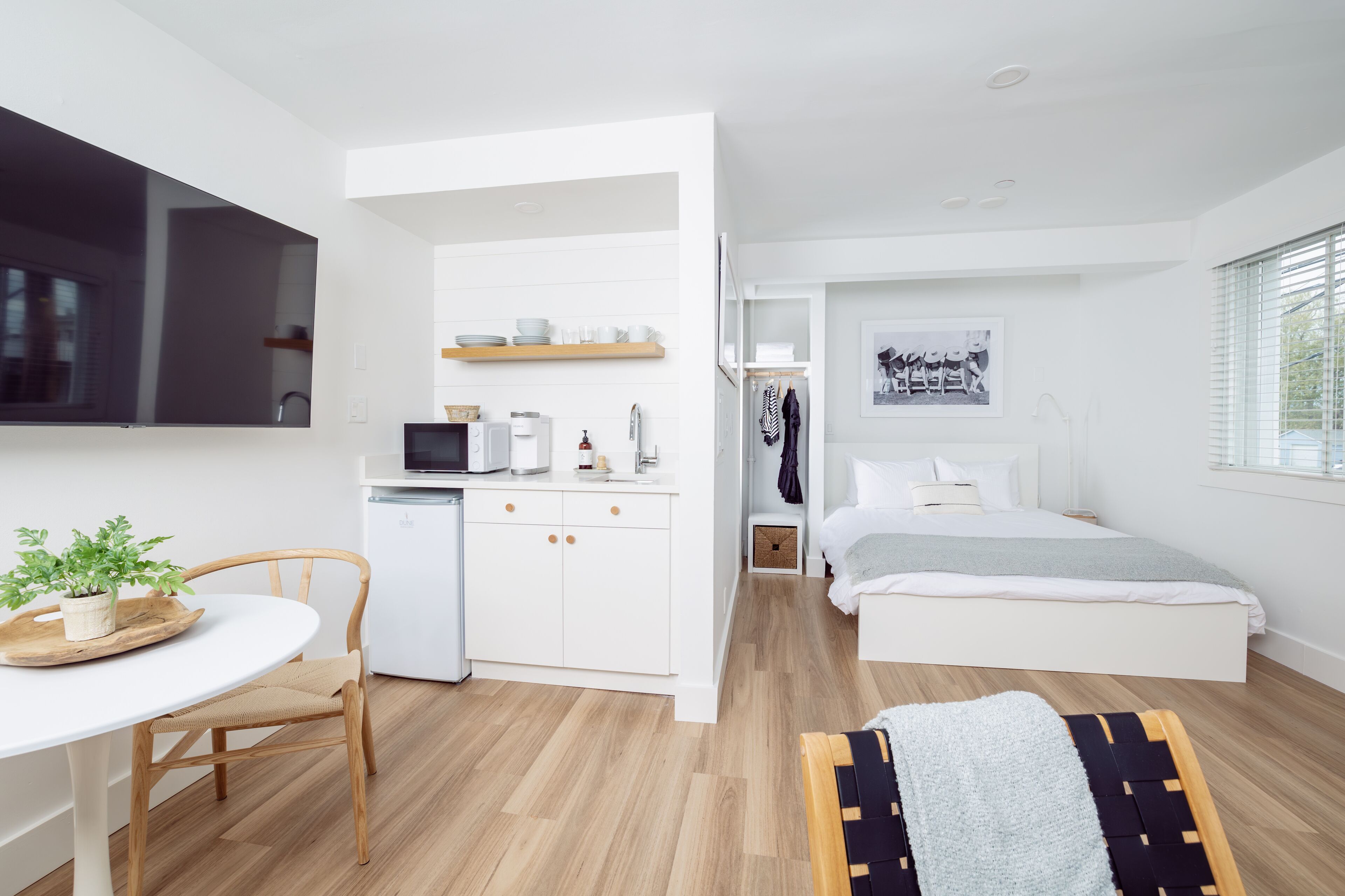 Un dormitorio moderno y minimalista con cama, mesita de noche y un pequeño espacio de escritorio.