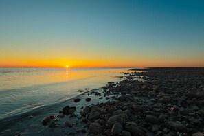 A rocky beach at sunset with calm water and a clear sky. - DUNE Fairfield Beach (Fairfield)