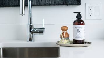 A bathroom sink with a modern faucet, a soap dispenser, and a soap dish with a brush.