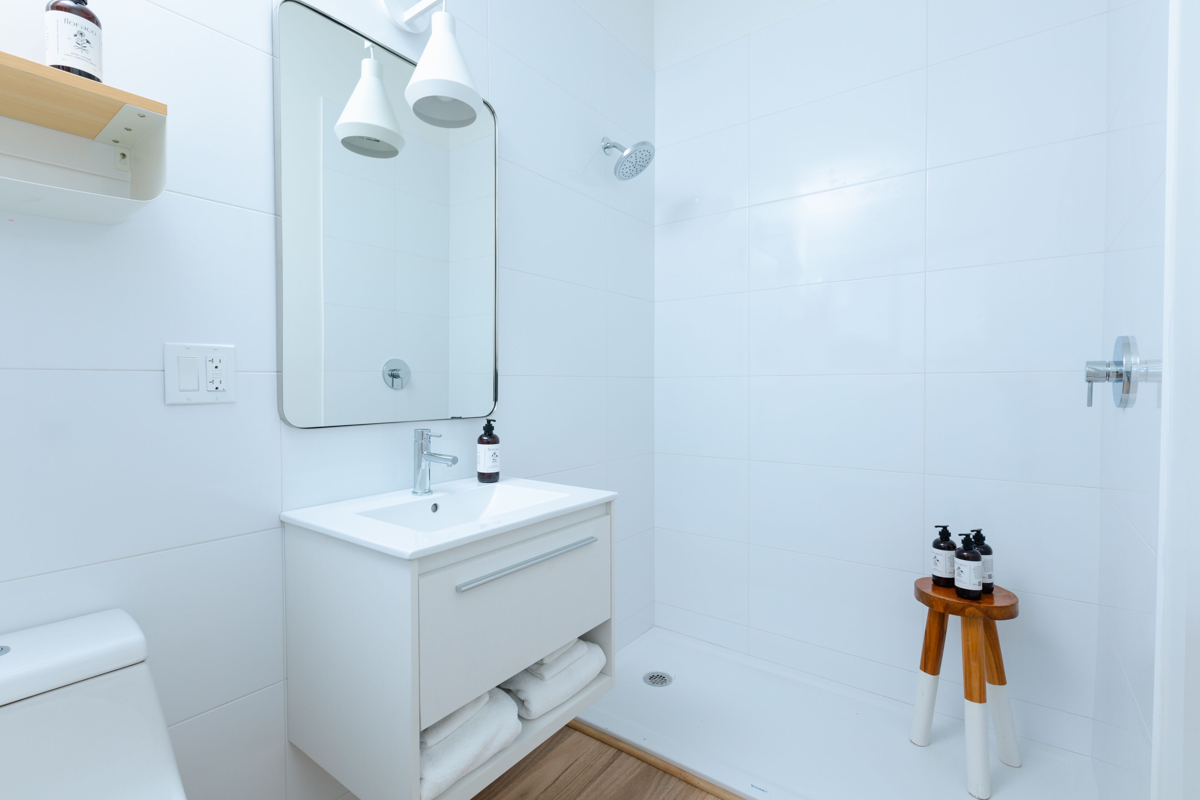 A modern bathroom with a white sink, mirror, and shower.