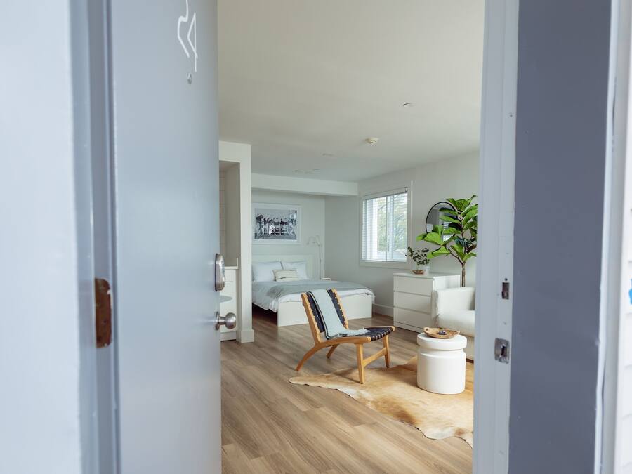 Una sala de estar moderna con piso de madera, un sofá blanco, una mesita de centro y un cuadro en la pared.