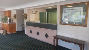 A reception area with a counter, a clock, a framed picture, and a plant.