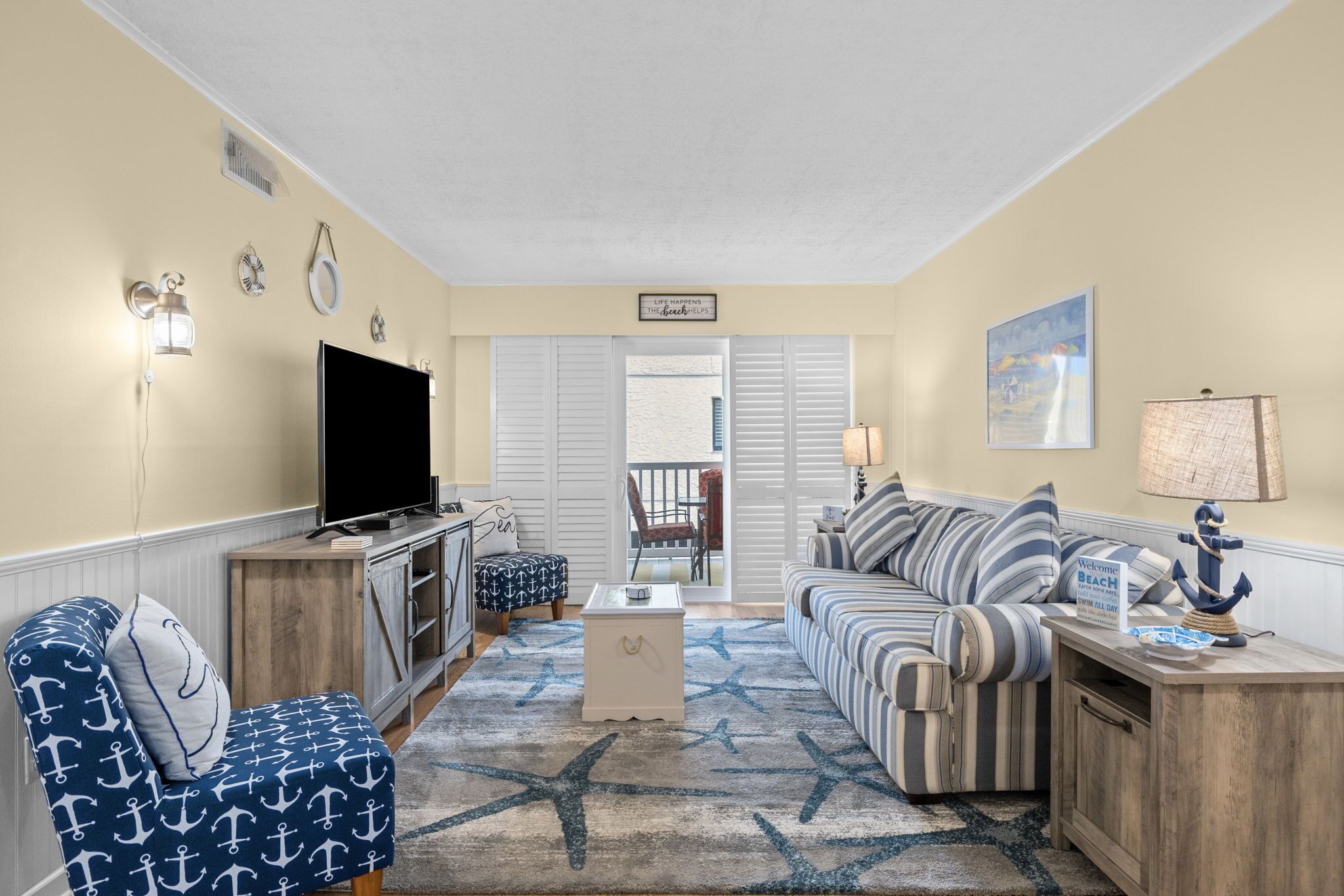 A living room with a TV, striped sofa, and a star-patterned rug.