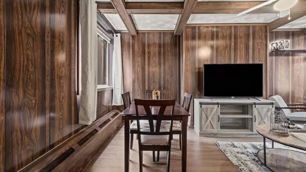 A modern living room with wooden paneling, a dining table with chairs, a flat-screen TV, and a coffee table. - 💜Lawrenceville Loft off Butler - Top Floor & Bespoke Woodwork💜 (Pittsburgh)