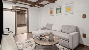 A modern living room with a sofa, coffee table, and artwork on the wall. - 💜Lawrenceville Loft off Butler - Top Floor & Bespoke Woodwork💜 (Pittsburgh)