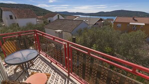 Un balcone con ringhiera rossa, un tavolo tondo e una sedia con cuscini.
