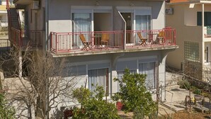 Un edificio a due piani con balconi, condizionatori d'aria e tetto in tegole.