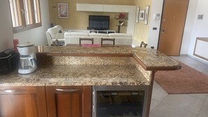 Eine Küche mit einer Granitarbeitsplatte, Holzausstattung, einer Kaffeemaschine und einem Essbereich mit einer Couch und Stühlen.