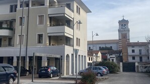 Ein mehrstöckiges Gebäude mit Balkonen, einer Straßenlaterne und einem Uhrturm.