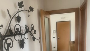 Ein Flur mit Holzboden, einer Tür zu einem Zimmer und einem an der Wand befestigten Ziermetallstück.